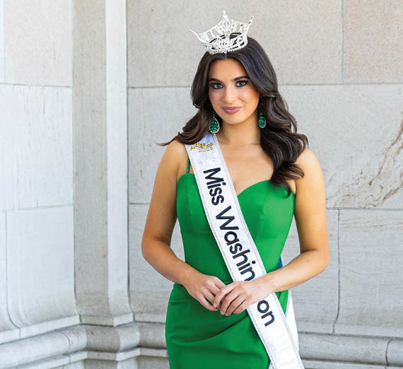 女性が窓の横で腕を組んで立っている